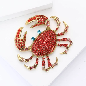 Makroansicht der Krabbenbrosche mit roten Strasssteinen und goldenem Finish