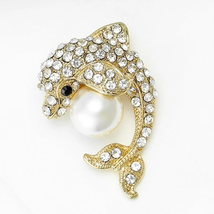 Macro d'une broche dauphin dorée ornée de strass brillants et d'une perle blanche