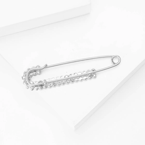 Close-up of silver alloy safety pin brooch with sparkling rhinestones and wavy edge