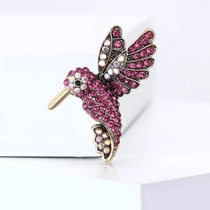 Macro shot of rose red and AB crystal hummingbird brooch with a polished gold finish