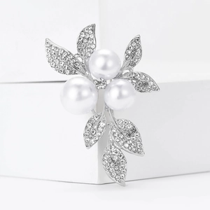 Macro detail of silver leaf brooch with three white pearls and pavé crystal setting