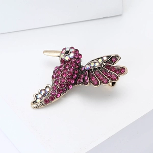 Detailed macro view of hummingbird brooch featuring purple rhinestones and golden alloy wings