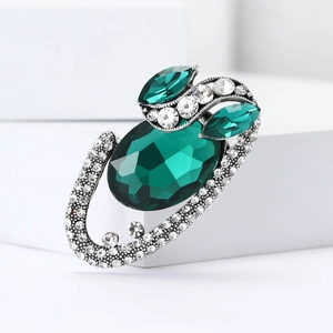 Vintage silver alloy oval brooch featuring a large emerald green gemstone and white rhinestones
