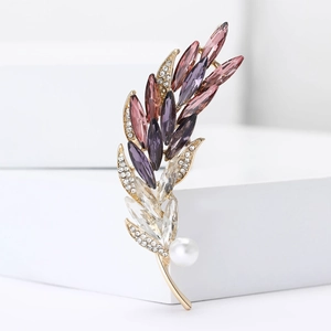 Elegant gold-tone feather brooch with purple crystals and pearl on geometric white stand