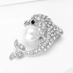 Vue macro de la broche dauphin avec strass étincelants et détail de grande perle blanche
