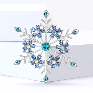 Eleganter silberner Schneeflocken-Anstecker mit blauen Strasssteinen auf weißem Sockel