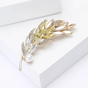 Macro detail of leaf brooch with champagne crystals, white pearl, and gold plating