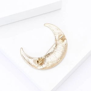 Detailed back view of golden crescent moon brooch with secure safety pin and texture