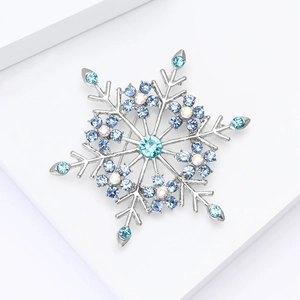 Eleganter Schneeflocken-Anstecknadel mit blauen Strasssteinen auf weißem Display