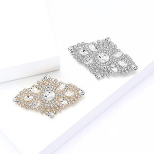 Elegant diamond-shaped rhinestone brooches in gold and silver finish on white pedestals