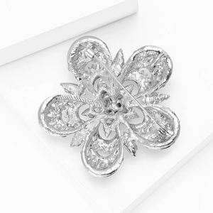 Vue détaillée du dos d'une broche fleur argentée avec fermoir épingle sur un bloc blanc