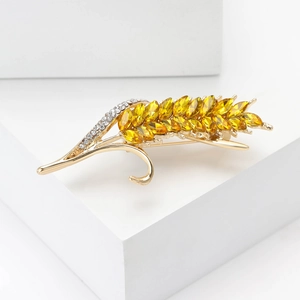 Broche épi de blé dorée élégante avec cristaux ambre sur support géométrique blanc
