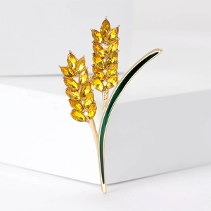 Elegant gold wheat brooch with amber crystals and green enamel on a clean white display