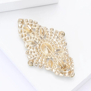 Detailed back view of golden vintage brooch showing hollow relief patterns and pin fastener