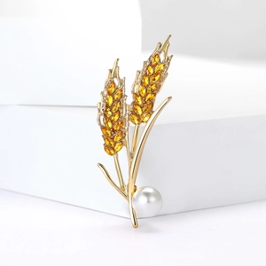 Elegant gold wheat brooch with amber rhinestones and a white pearl on a white pedestal