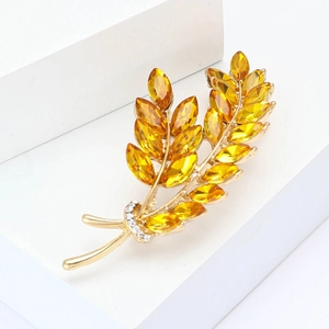 Élégante broche en blé doré avec cristaux d'ambre et zircons blancs sur fond blanc