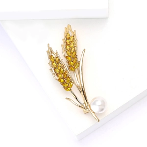 Détail macro de la broche épi de blé dorée avec cristaux jaunes et perle blanche