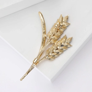 Detailed view of golden wheat stalk brooch with refined relief texture and brushed finish