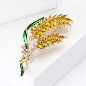 Macro view of golden wheat brooch with yellow crystal grains and green enamel leaves