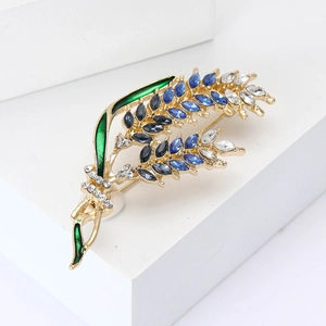 Detail of elegant wheat ear brooch with blue crystals and green enamel on golden alloy base
