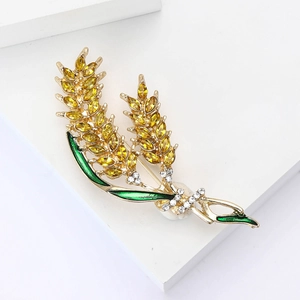 Detail of wheat ear brooch with amber rhinestones and green enamel on golden alloy base