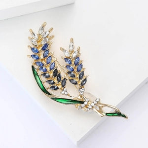 Detail of elegant double-headed wheat ear brooch with blue crystals and green enamel leaf