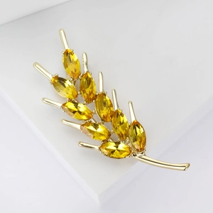 Élégante broche blé dorée avec pierres jaunes sur socle blanc minimaliste