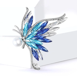 Élégante broche papillon argentée avec cristaux bleus et perle blanche sur socle