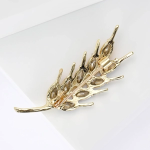 Broche élégante en forme d'épi de blé doré avec cristaux sur un support de bijoux moderne