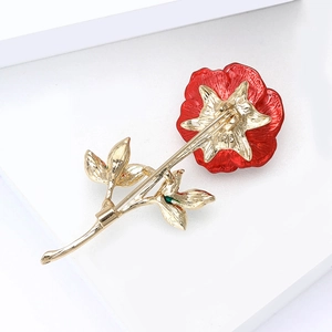 Elegant red enamel rose brooch with gold leaves and secure pin back on white background