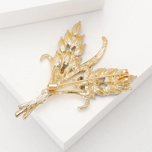 Golden leaf-shaped alloy brooch featuring a detailed back structure and safety pin clasp