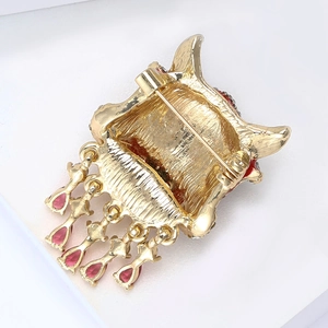 Vue détaillée du dos d'une broche en alliage doré avec pendentifs rouges en gouttes