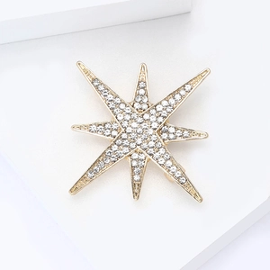 Detailed close-up of gold eight-pointed star brooch with sparkling white rhinestones