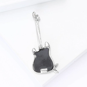 Macro view of guitar brooch with silver alloy base and black enamel finish details