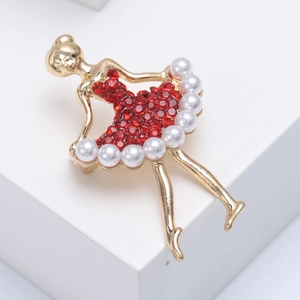 Dettaglio macro di spilla ballerina dorata con cristalli rossi e piccole perle bianche