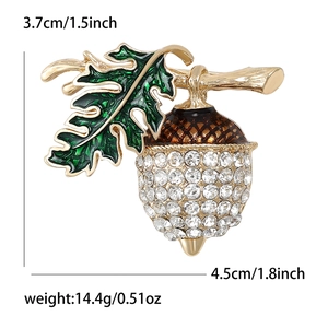 Golden chestnut brooch with green enamel leaf and white rhinestones on white background