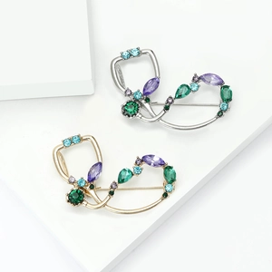 Broches stéthoscope élégantes en or et argent avec strass colorés sur support blanc