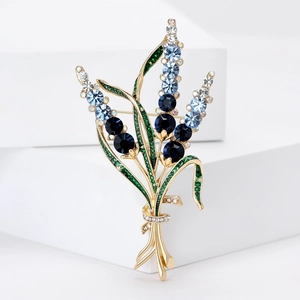 Broche élégante en alliage doré avec strass bleus présentée sur support blanc