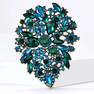 Detail of vintage flower brooch with emerald and sapphire rhinestones in antique bronze