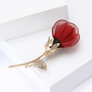 Detailed close-up of a red mesh rose brooch with gold stem and sparkling rhinestones