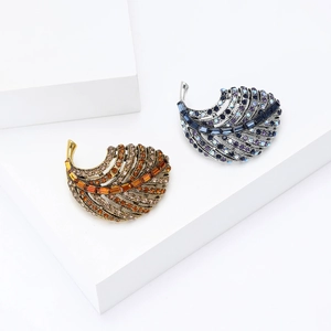 Elegant gold and silver feather brooches with rhinestones on a minimalist white background