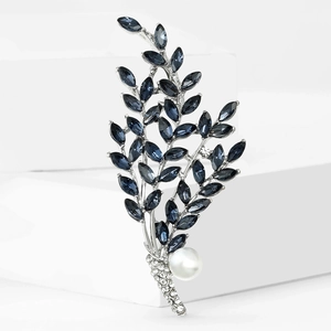 Elegant silver leaf brooch with deep blue crystals and white pearl on minimalist stand