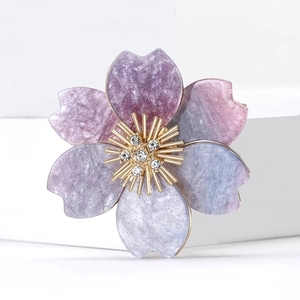 Close-up of elegant acrylic flower brooch with purple resin petals and gold stamen details