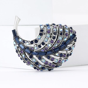 Elegant silver feather brooch with blue and purple rhinestones on a white pedestal