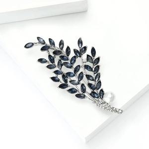 Detailed close-up of alloy leaf brooch with navy marquise stones and a white pearl accent