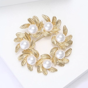 Detailed view of the gold leaf wreath brooch featuring elegant white pearls and fine textures