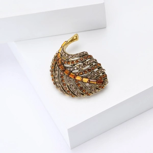 Macro shot of vintage leaf brooch with amber rhinestones and gold metal vein details