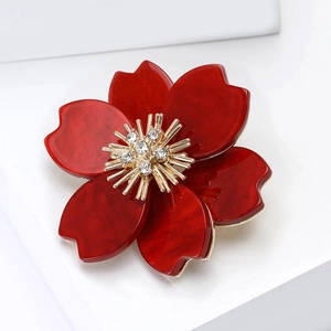 Detailed macro view of dark red acrylic flower brooch with golden rhinestone center