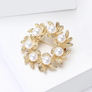 Macro detail of golden leaf wreath brooch featuring intricate leaf veins and white pearls