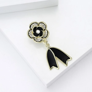 Detail of luxury camellia brooch with black enamel, white rhinestones and a bow pendant